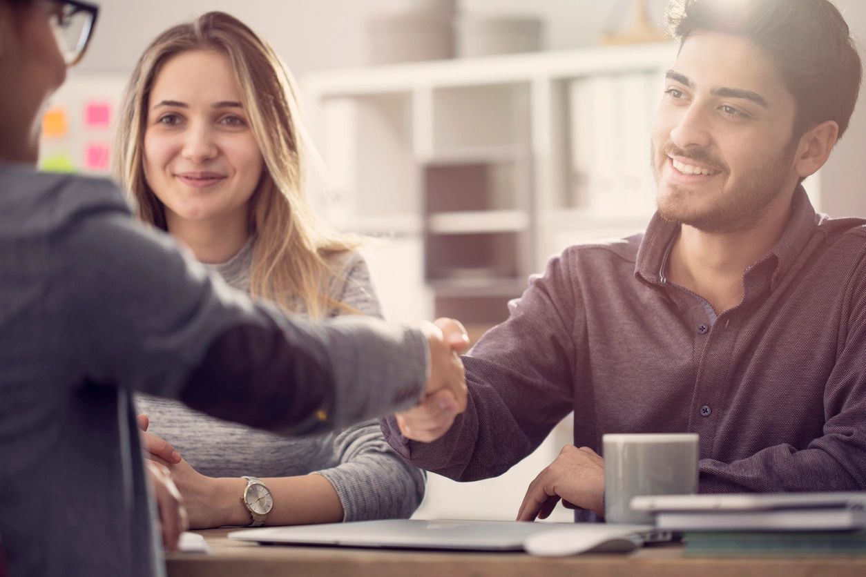 Young couple shaking hands with a female agent